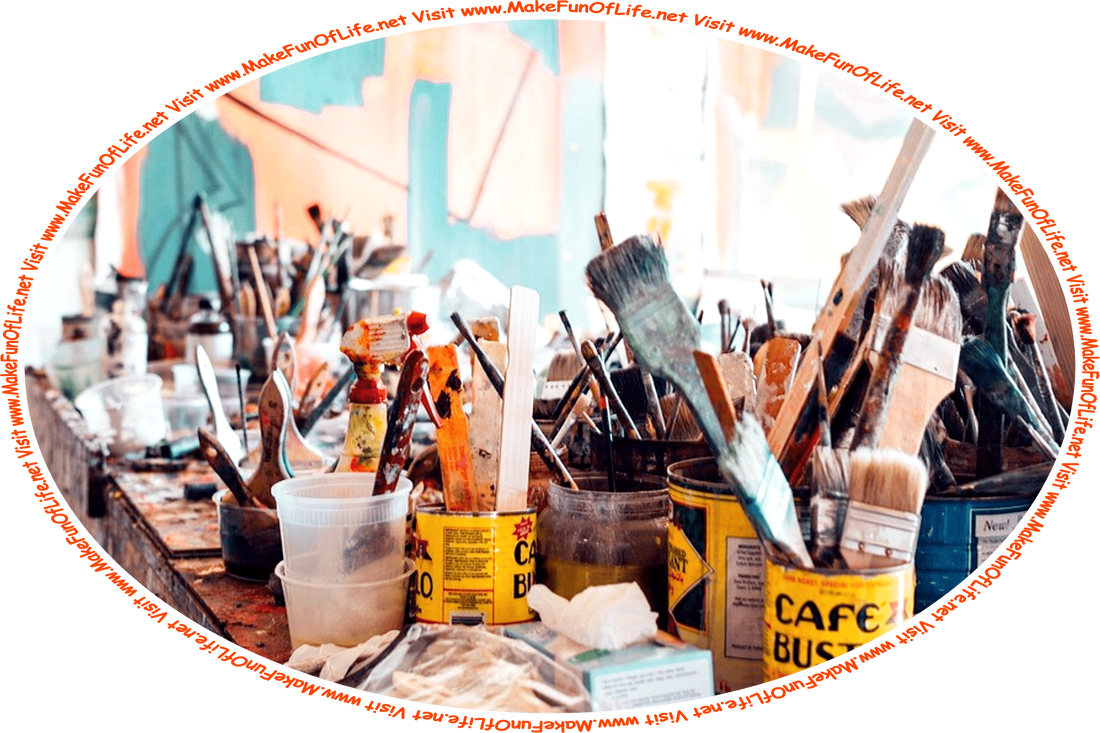 Picture of a messy table covered with metal and plastic containers holding paintbrushes and stirring sticks of various sizes, with splatters and spots of paint everywhere, inside an artist’s studio, and the words, ‘Visit www.MakeFunOfLife.net.’